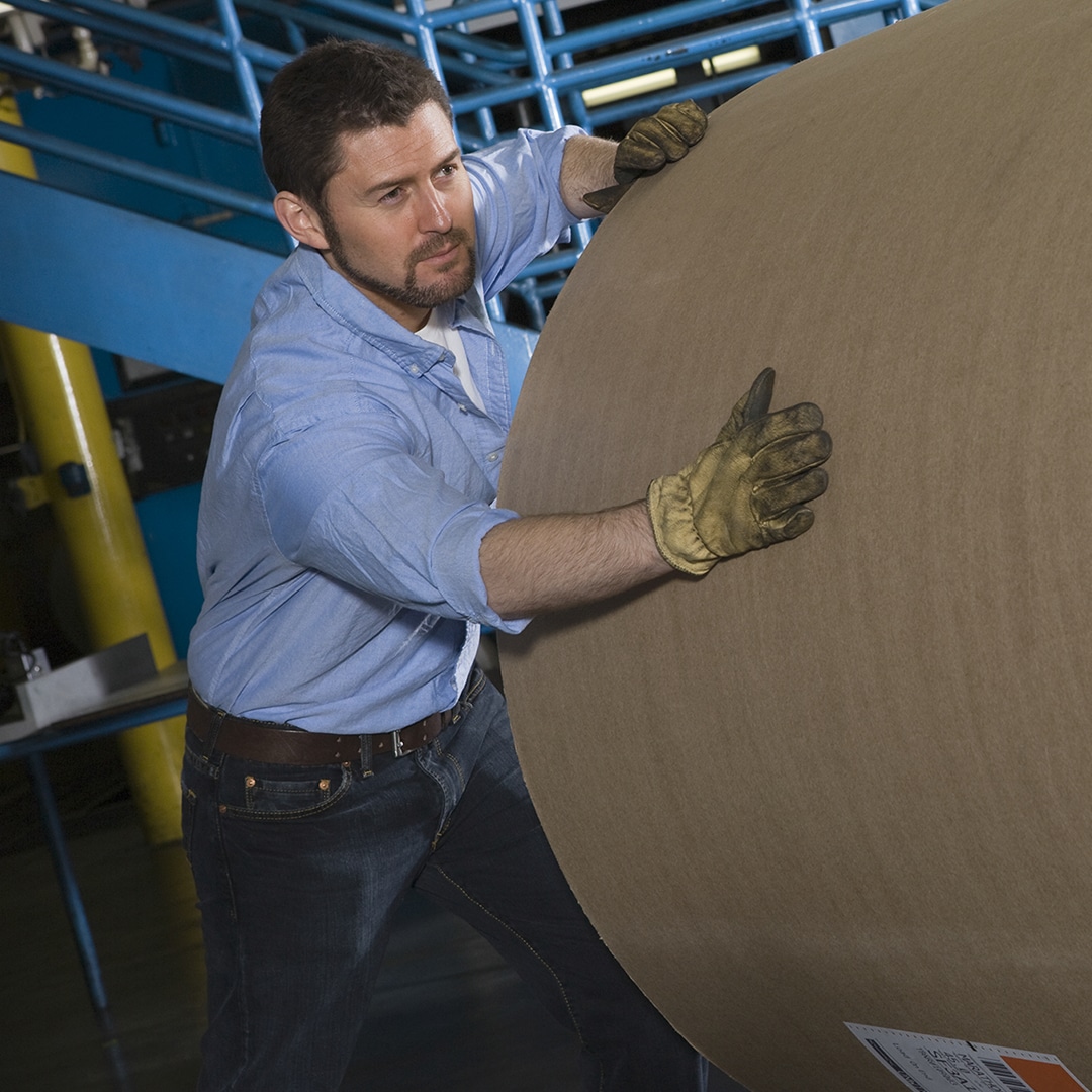 Image of a worker with a large spool of paper