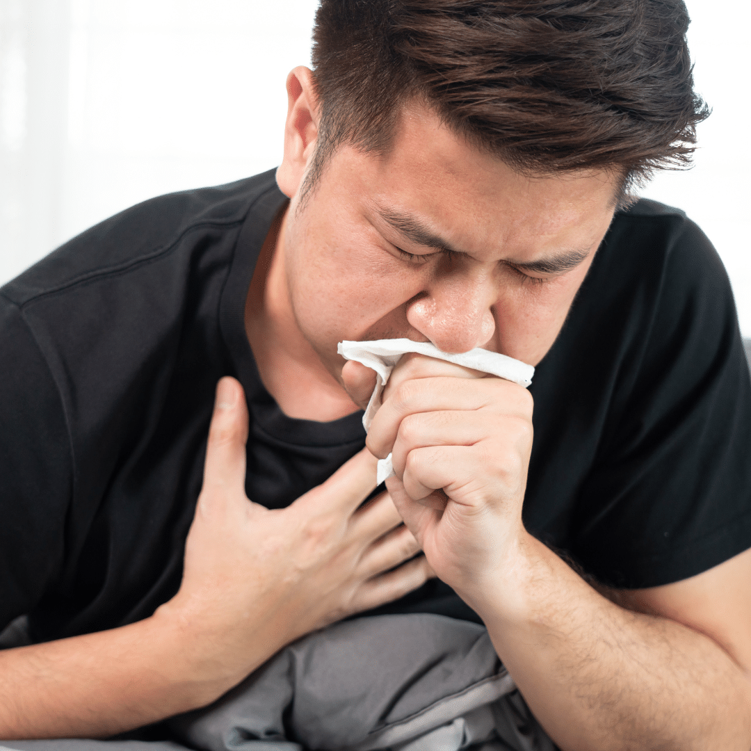 A man coughing into a tissue