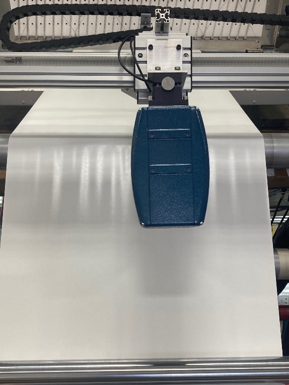 MoistTech IR3000 sensor traversing across coated packaging material for coat weight measurement.
