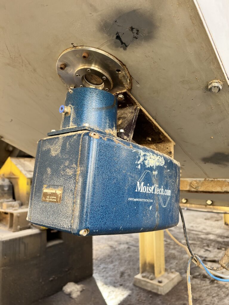 Close-up of MoistTech moisture sensor mounted beneath wood pellet processing equipment.