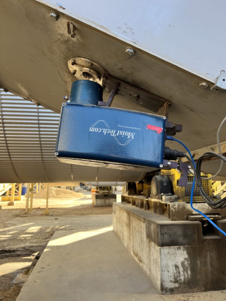 MoistTech online moisture sensor mounted beneath wood pellet production equipment for continuous moisture monitoring.