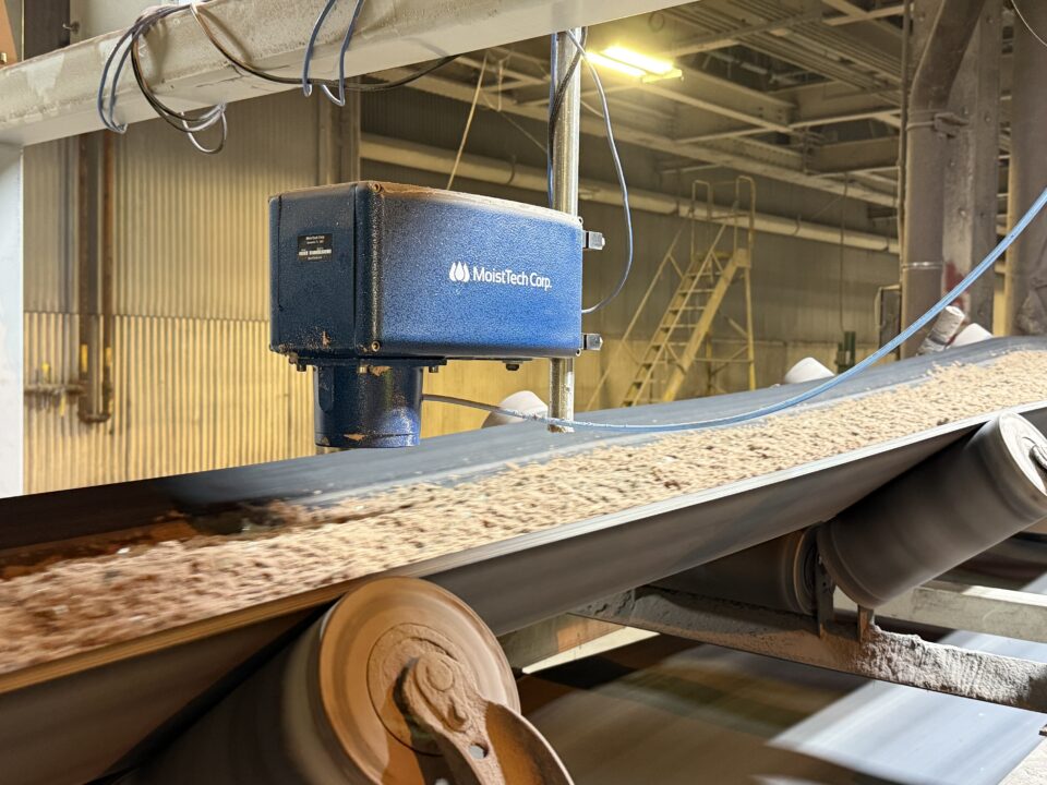 MoistTech NIR moisture sensor installed above a conveyor carrying granular glass batch material