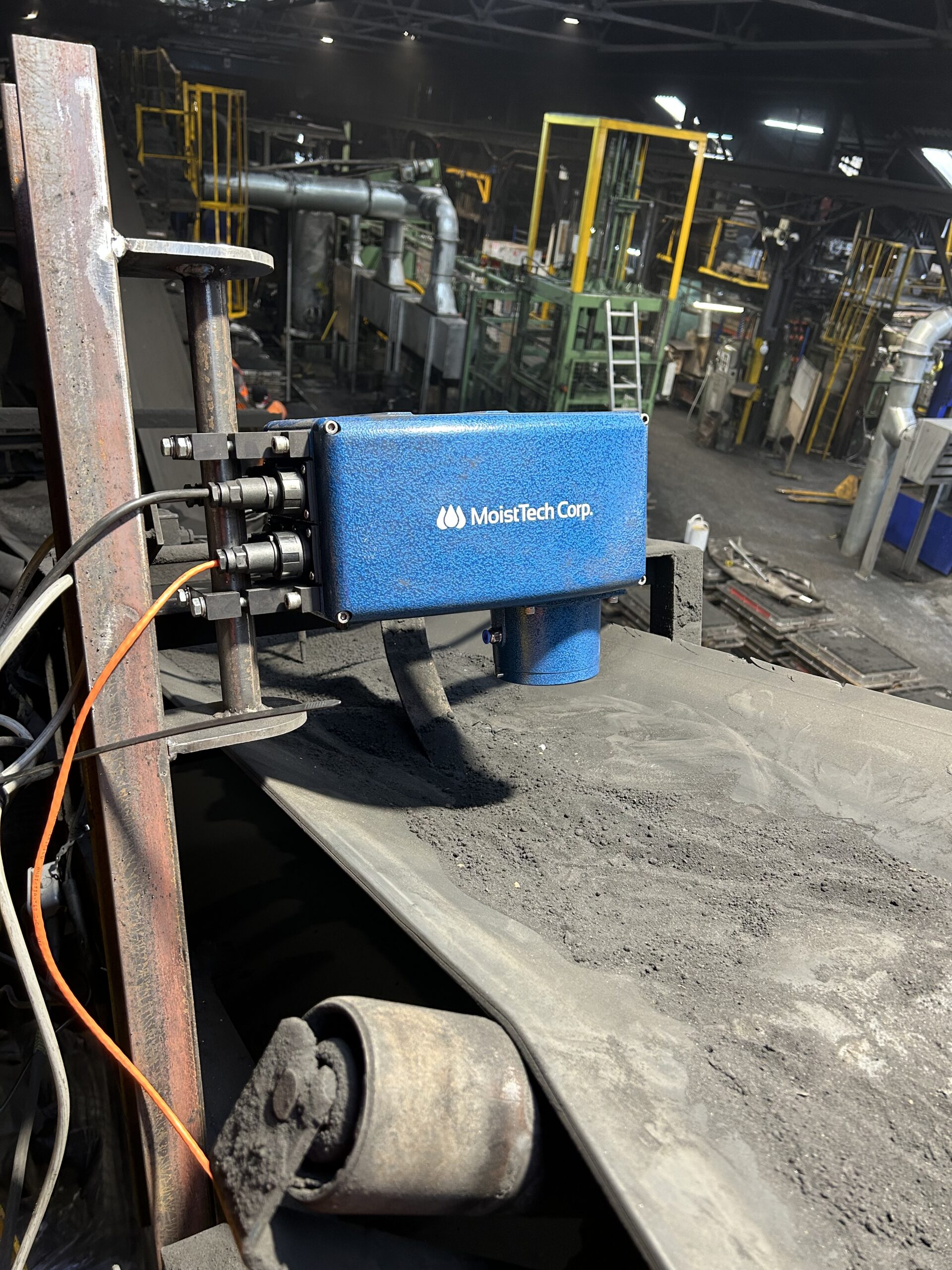 MoistTech IR-3000 NIR moisture sensor installed above a conveyor carrying foundry sand